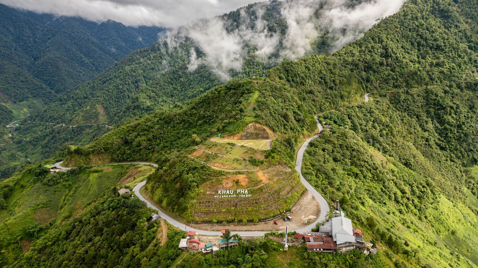 The Khau Pha pass from above, the road doubling back around a spur with the name spelled out in white letters on the hillside below the bend