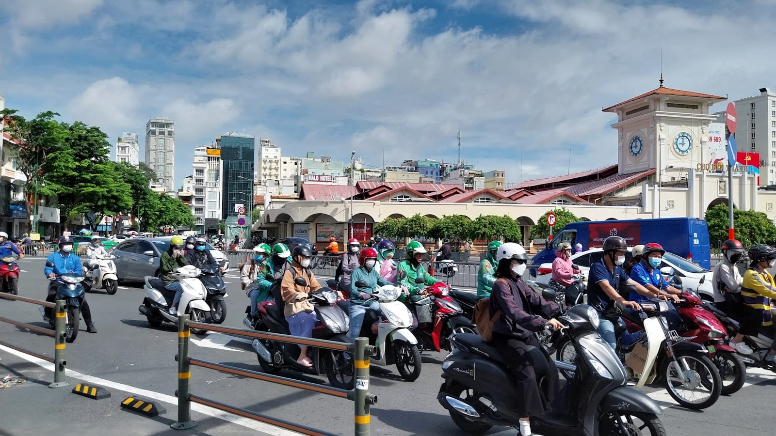 Scooters waiting at a junction in front of Ben Thanh market's clock tower