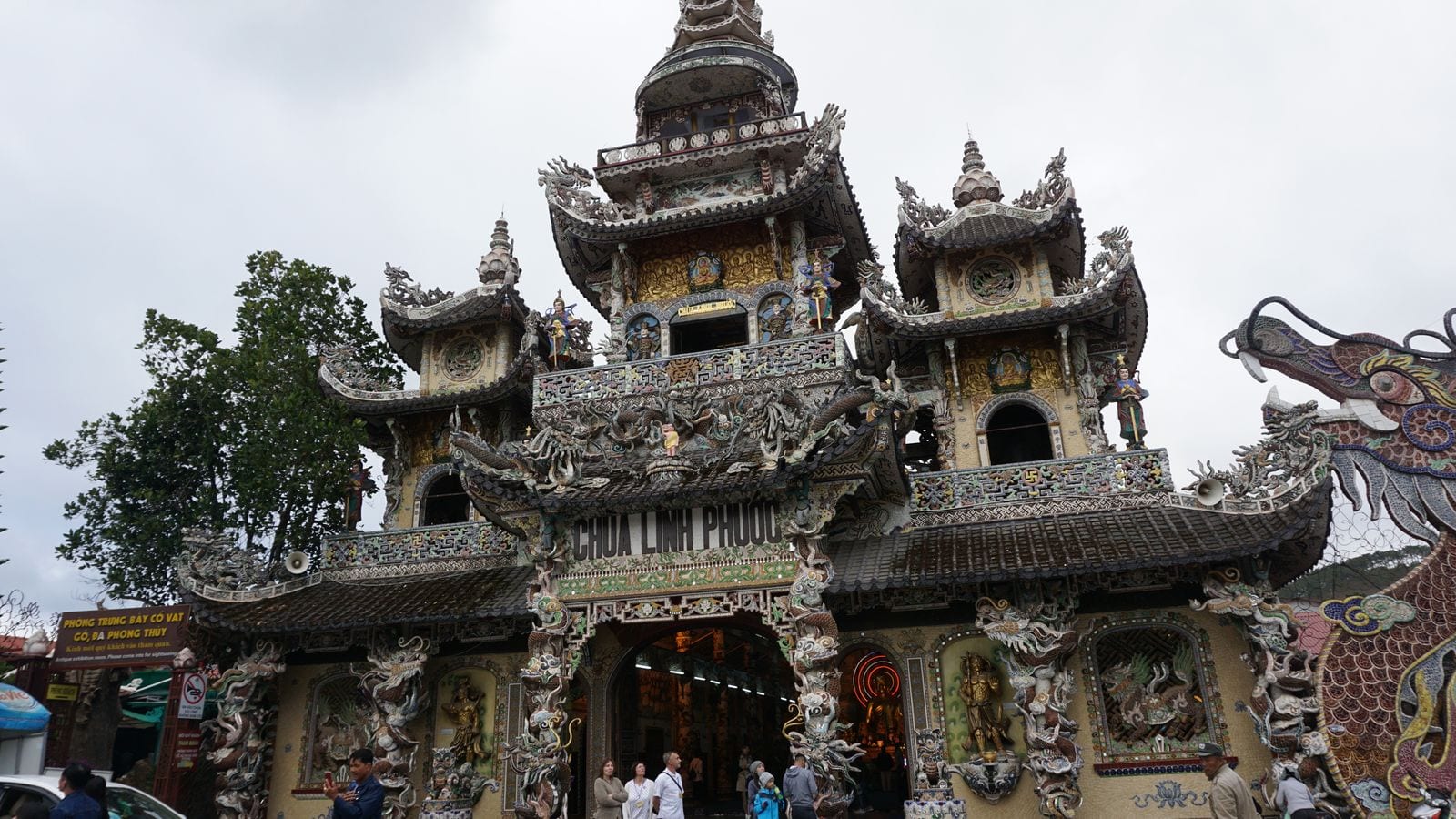 The front of Chua Linh Phuoc, every surface covered in broken ceramic mosaic, with a dragon built out of bottle shards running along the terrace to the right