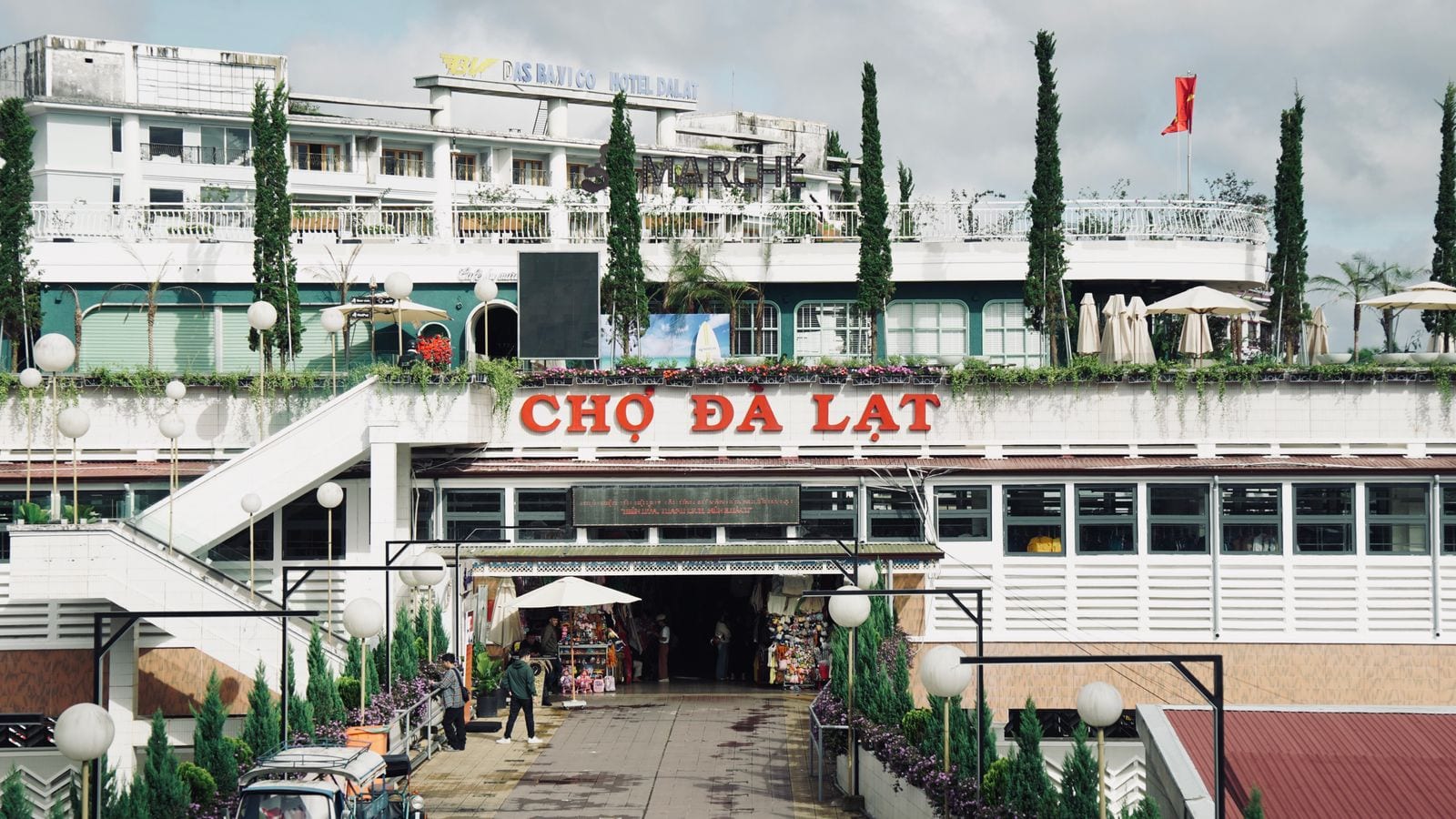 The entrance to Da Lat market under red lettering reading CHO DA LAT, a Vietnamese flag on the roof behind
