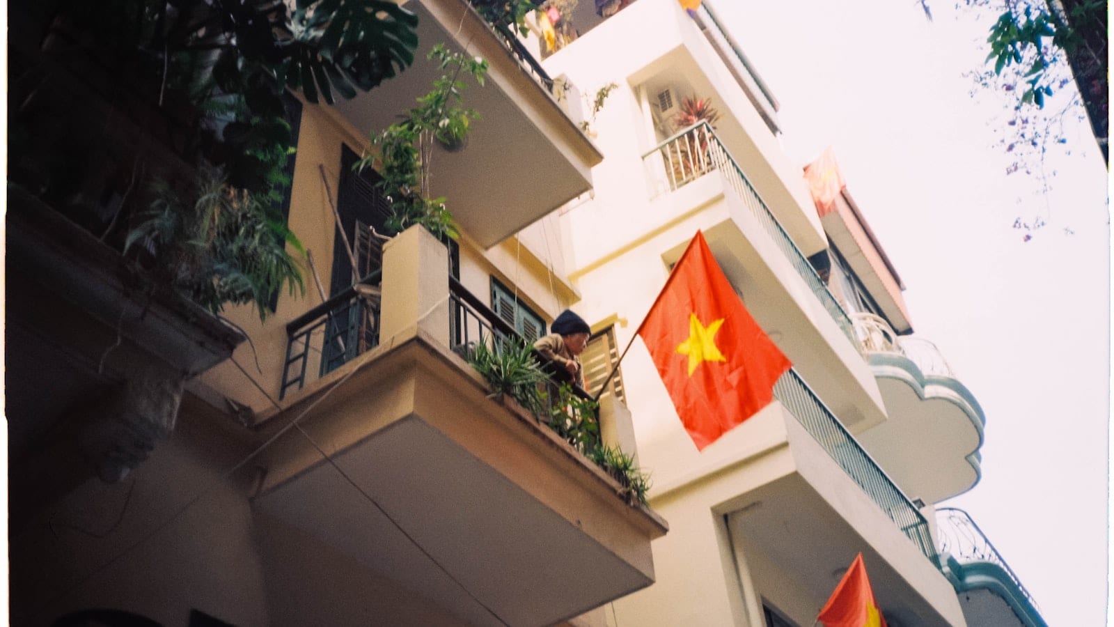 Balconies of a narrow Vietnamese apartment block, a national flag hanging from one