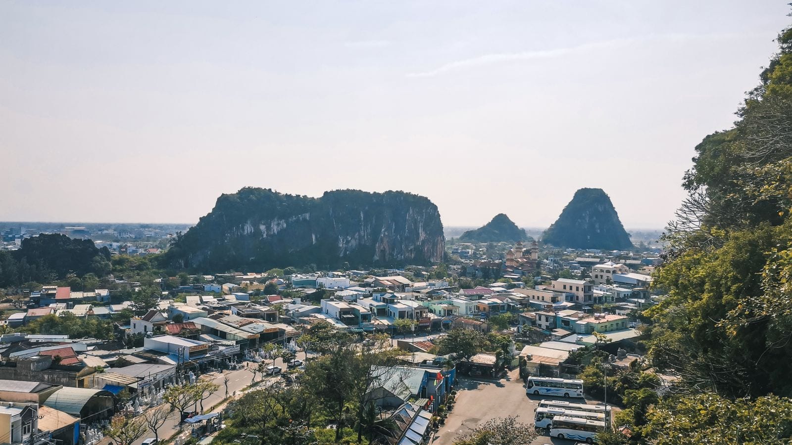 The limestone outcrops of the Marble Mountains rising over the stone-carving village on the road between Da Nang and Hoi An, coaches parked below
