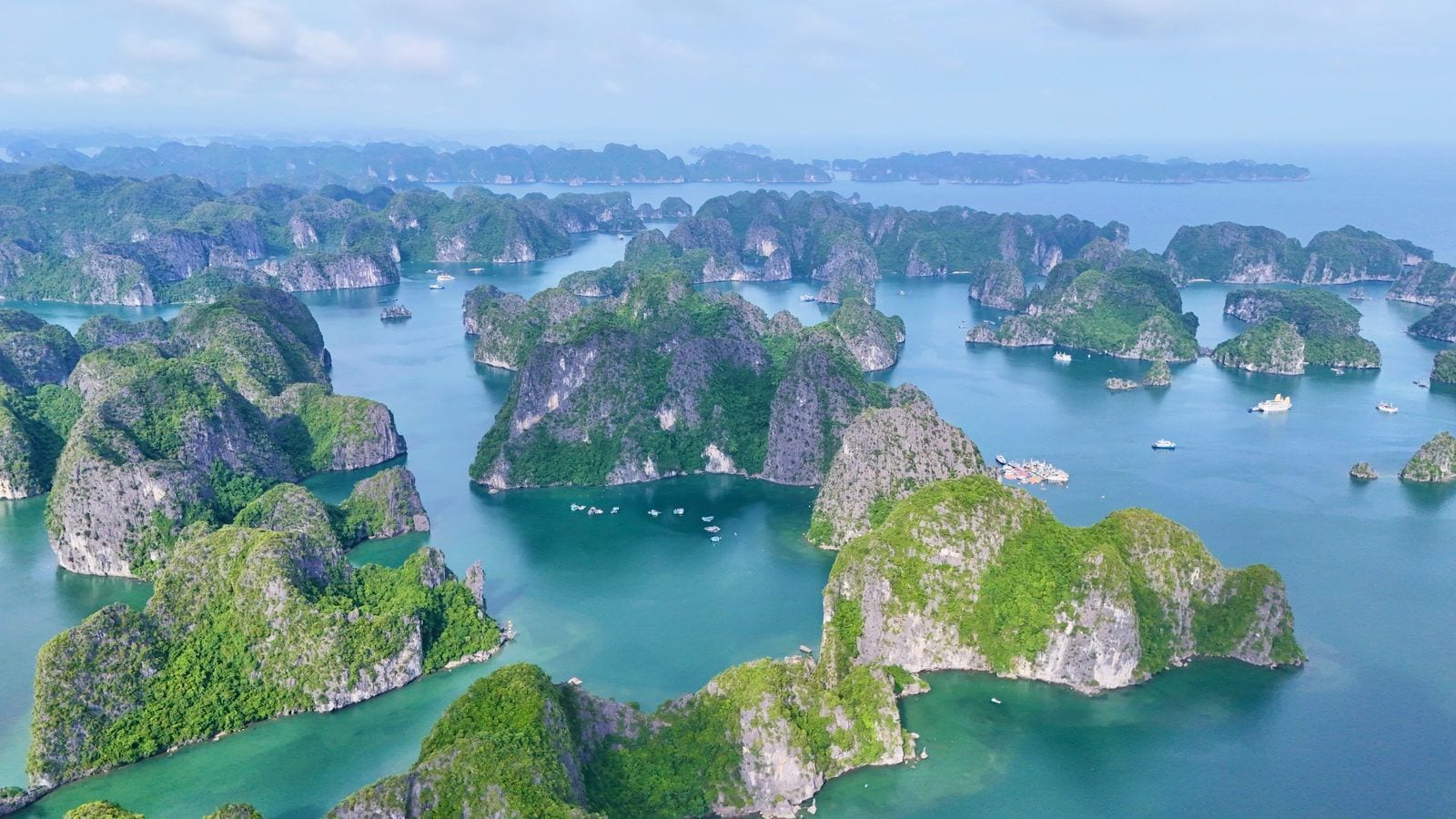 Limestone islands crowding the green water of the bay off Cat Ba, cruise boats anchored between them