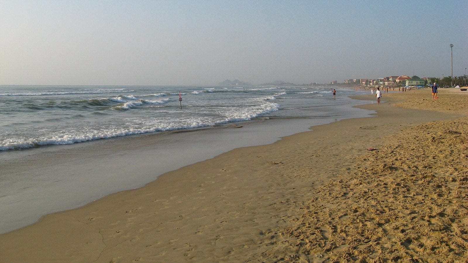 My Khe beach running north into the haze, small surf along an empty stretch of sand and the Da Nang seafront in the distance