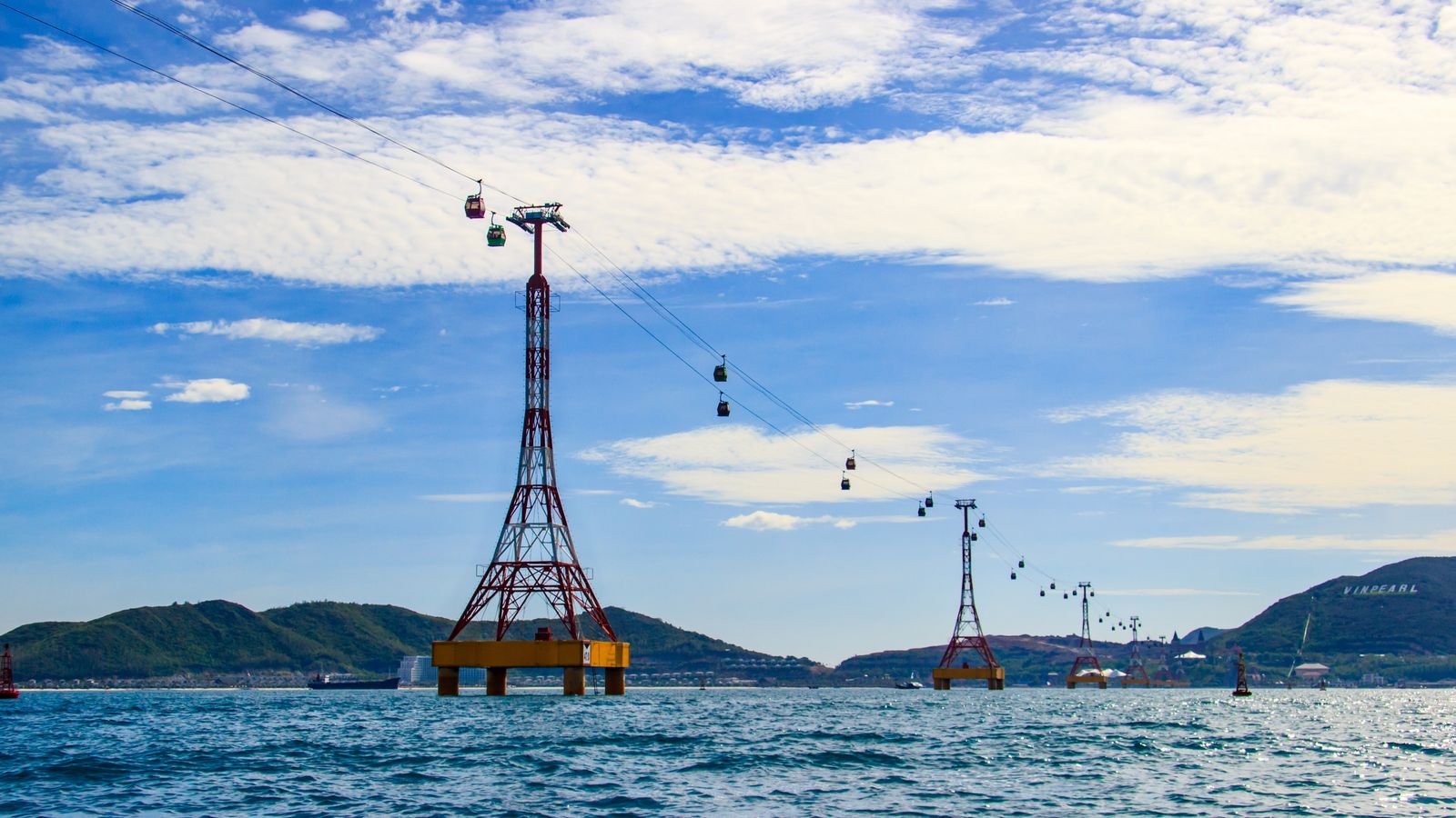 The over-water cable car crossing Nha Trang bay on red pylons, with the VINPEARL sign on the hillside opposite